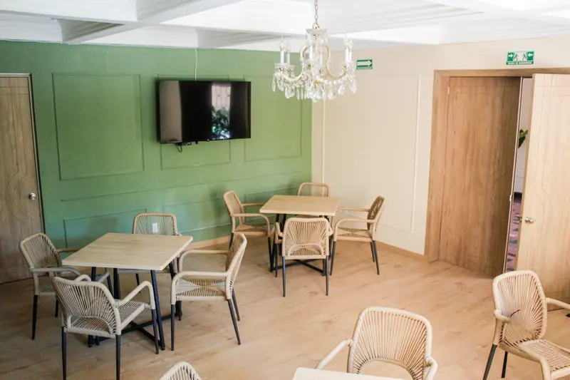 Sala de usos múltiples con mesas de actividades y televisión